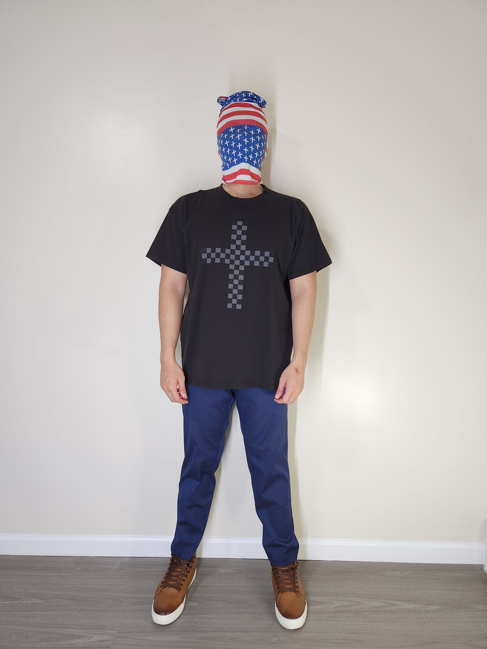 Model wearing black Damier Cross T-shirt, blue pants, and brown boots, front view